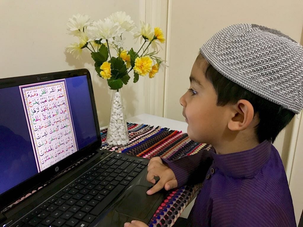 Young boy reading Quran online on a laptop